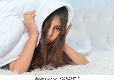 Portrait Of Cute Girl Covering Head Trying To Sleep In Noisy Room