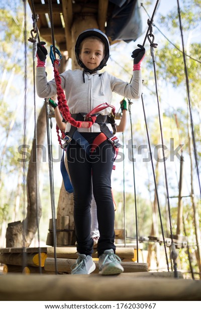 Portrait of\
cute girl crossing zip line on a sunny\
day