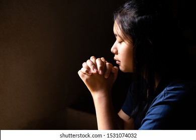 Portrait of a cute girl praying with her eyes closed