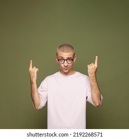 Portrait Of Cute Guy In Glasses Pointing Up At Copy Space On Green Background