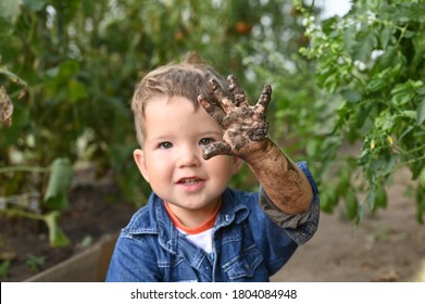 Portrait Of Cute Happy Boy Showing His Muddy Hand.