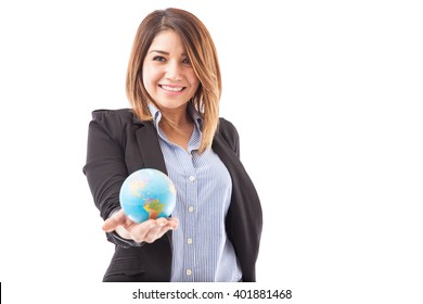 Portrait of a cute and happy female travel agent holding a small globe in her hand and smiling