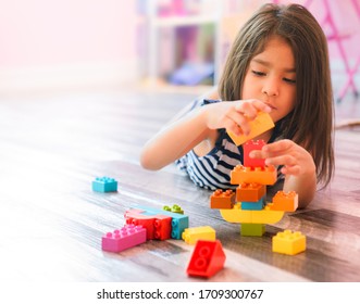 Portrait Of A Cute Happy Little Preschool Hispanic Girl Playing Alone With Colorful Construction Blocks In Her Bedroom Floor At Home. Child Developing Motor Skills With Games Copy Space