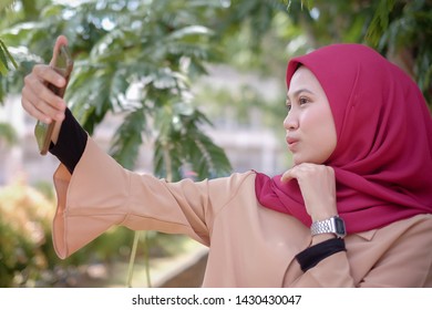 Portrait Of A Cute Happy Malay  Girl  In A Veil With Style Makes Selfie On A Smartphone Smile