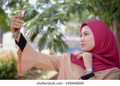 Portrait Of A Cute Happy Malay  Girl  In A Veil With Style Makes Selfie On A Smartphone Smile