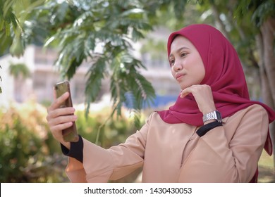 Portrait Of A Cute Happy Malay  Girl  In A Veil With Style Makes Selfie On A Smartphone Smile