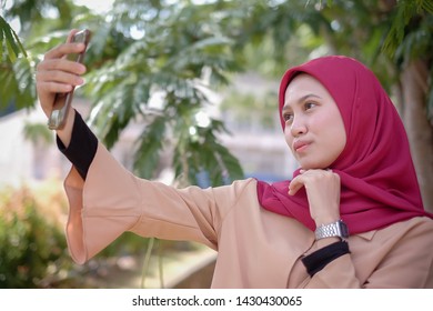 Portrait Of A Cute Happy Malay  Girl  In A Veil With Style Makes Selfie On A Smartphone Smile