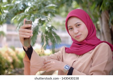 Portrait Of A Cute Happy Malay  Girl  In A Veil With Style Makes Selfie On A Smartphone Smile