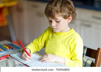 Portrait Of Cute Happy School Kid Boy At Home Making Homework. Little Child Writing With Colorful Pencils, Indoors. Elementary School And Education. Kid Learning Writing Letters And Numbers.