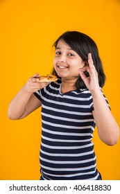 Portrait Of Cute Indian Girl Eating Pizza Over Yellow Background