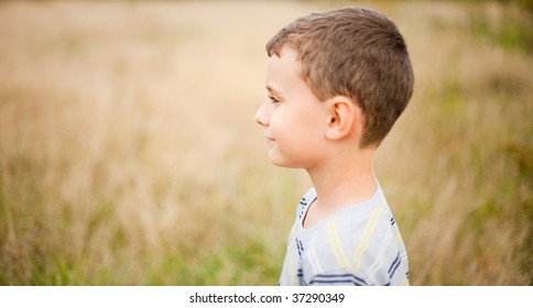 Portrait Of A Cute Kid In Profile, Over A Blurred Nature Background