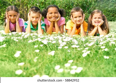 Portrait of cute kids lying on green grass and looking at camera