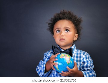 Portrait of cute little African boy holding in hands small globe on blackboard background, back to school concept - Powered by Shutterstock