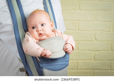 Portrait of a cute little baby girl in a sling looking at the camera. - Shutterstock ID 2366953891