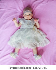 Portrait Of A Cute Little Baby Girl Princess A Crown On The Head Lying Pink Background