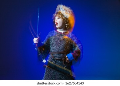 Portrait Of A Cute Little Boy Dressed As A Medieval Knight With A Sword. Kid Medieval Warrior, Baby In Knight Costume. Medieval Festival Or Costume Party For Kids.