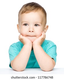 Portrait of a cute little boy looking at something while supporting his head with both hands, isolated over white