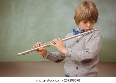 Portrait of cute little boy playing flute in classroom - Powered by Shutterstock