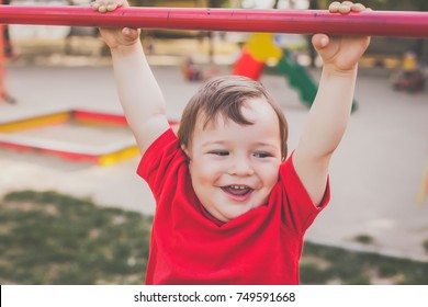 portrait of cute little boy in red t-shirt playing and smiling on playground. concept of happy healthy child