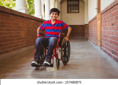 Portrait of cute little boy sitting in wheelchair in school corridor - Powered by Shutterstock