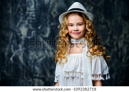 Portrait of a cute little girl with beautiful curly hair. Kid's fashion, style.