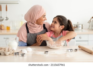 Portrait Of Cute Little Girl Helping Islamic Mom Baking In Kitchen, Happy Arab Female Child Kneading Dough For Cookies, Preparing Pastry With Her Muslim Mother At Home, Closeup Shot With Free Space