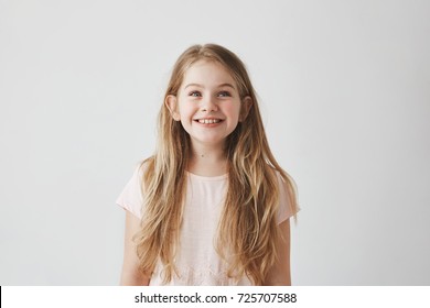 Portrait Of Cute Little Girl With Long Light Hair Smiling Brightfully, Looking Upside On Colorful Flying Balloons With Happy And Excited Expression.