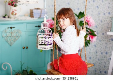 Portrait Of A Cute Little Girl Ride On A Swing In The Interior With Shabby Chic Decor