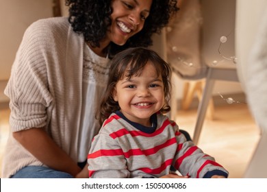 Portrait Of An Cute Little Girl Smiling While Sitting In A Blanket Fort With Her Mother On Their Living Room Floor At Home