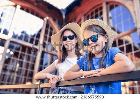 Portrait of a cute little girl wearing hat and sunglasses with her sister outdoors.