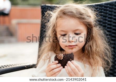 portrait of a cute little girl who hid from her parents and ate sweet cakes as harmful to children in large quantities