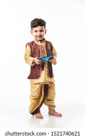 Portrait Of Cute Little Indian Boy In Traditional Wear Using Smartphone / Mobile Playing Games Or Watching Videos, Isolated Over White Background