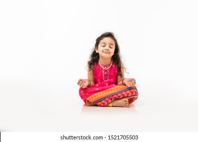 Portrait of cute little Indian girl model practicing and posing for pranayama or meditation while sitting isolated over white background with eyes closed - Powered by Shutterstock