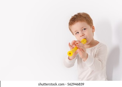 Portrait Of Cute Little Kid Boy In White Shirt Playing The Flute On White Background. Music And Lifestyle Concept