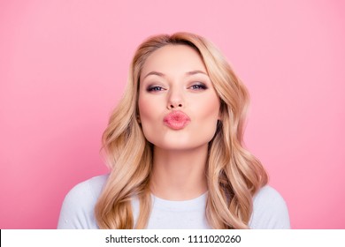 Portrait of cute lovely girl in casual outfit with modern hairdo sending blowing kiss with pout lips looking at camera  isolated on pink background. Affection feelings concept