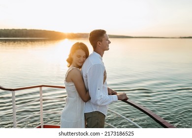 The portrait of cute loving couple hugging in the white boat in lake at sunset. Summer vacation, love, kissing, honeymoon. Beautiful view, warm sunlight, blue water of sea. emotional man and woman.