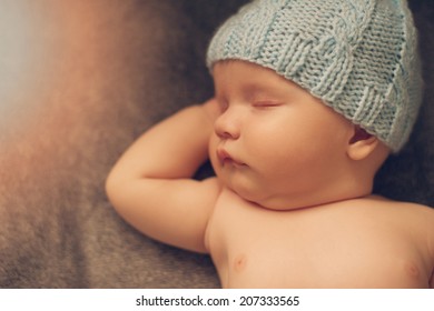 Portrait of cute newborn baby in a knitted hat with hands