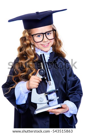 Portrait of a cute nine year old girl in an academic gown and hat holding a microscope. Educational concept. Isolated over white.