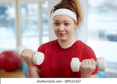 Portrait Of Cute Overweight Woman Working Out In Fitness Studio:  Doing Weightlifting Exercise With Dumbbells