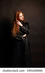Portrait of cute red haired young Woman.Attractive young Girl with long red hair on a dark background.Fashion portrait of beautiful red haired fashion Model girl with long hair in black leather coat