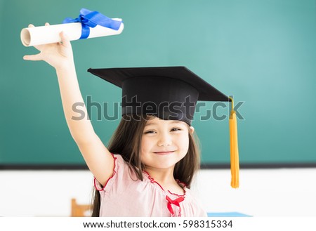 Portrait of  cute schoolgirl with graduation hat in classroom