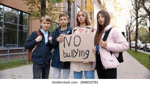 Portrait Of Cute Serious Teen Schoolkids Standing Outdoors Near School With 