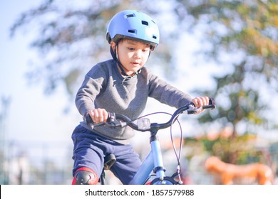 Portrait of cute small active asian boy wearing sport helmet riding small bicycle for kid alone in outdoor park during beautiful sunny days - Powered by Shutterstock