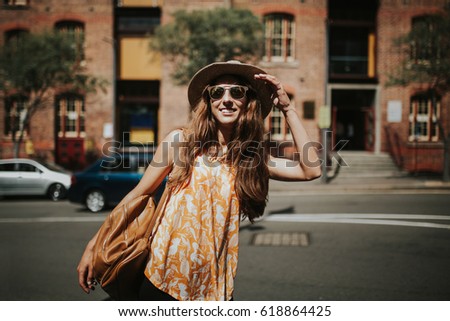 Blonde thin woman with hat and sunglasses visiting the city during the day.