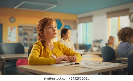 Portrait of a Cute Smiling Redhead Girl Sitting Behind a Desk in Class in Elementary School. Young Pupil is Looking at Camera, Smiling. Kids Educated in Modern Primary School - Powered by Shutterstock