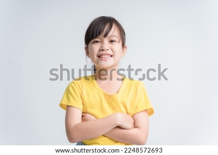 Portrait of cute swarthy asian little girl, arms crossed, beautiful happy child smiling and laughing looking at camera isolated in studio
