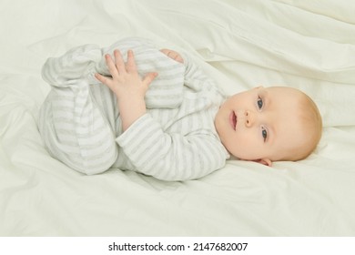 Portrait Of A Cute And Sweet Newborn Baby Lying On A Bed And Looking Calmly At The Camera. Happy Babyhood. 