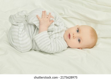 Portrait Of A Cute And Sweet Newborn Baby Lying On A Bed And Looking Calmly At The Camera. Happy Babyhood. 