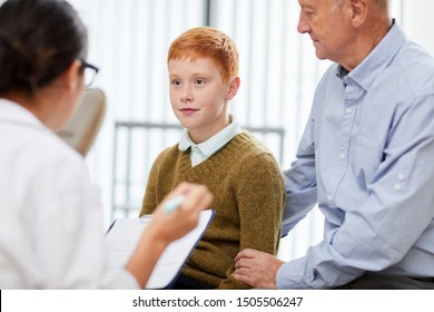 Portrait Of Cute Teenage Boy Visiting Doctor With Father And Looking At Nurse Filling Patients Form In Waiting Room, Copy Space