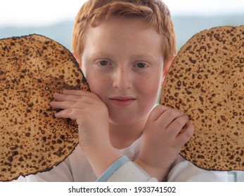 Portrait Of The Cute Teenager Boy Holding Matzah. Jewish Child Eating Matzo Unleavened Bread In Jewish Holidays Passover.